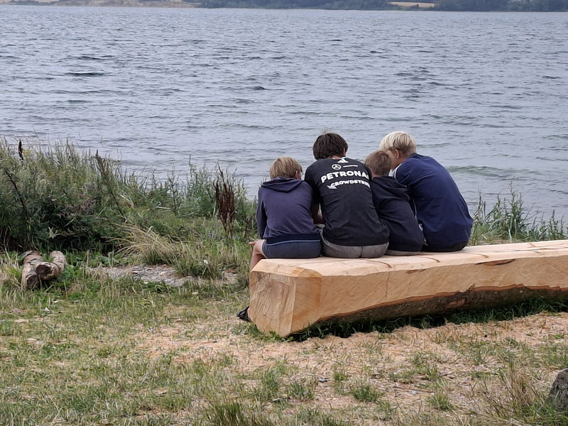 Tre mennesker sidder ved vandet på Barsø